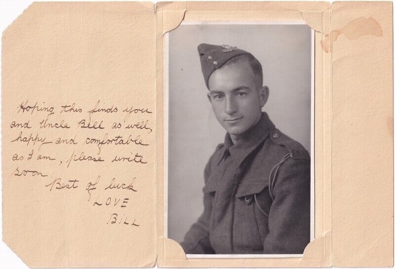 The image features a sepia-toned photograph of a young man in military attire on the right side, enclosed in an aged paper frame with rounded corners. He is wearing a uniform with visible buttons and shoulder straps, and a cap with an insignia. The backdrop is plain, emphasizing the subject. On the left side, there's handwritten text on the aged paper, which has a slightly textured surface. The paper is folded to create a card-like appearance, and there is a small tear at the bottom right corner. A brownish stain is visible on the top right side of the paper.