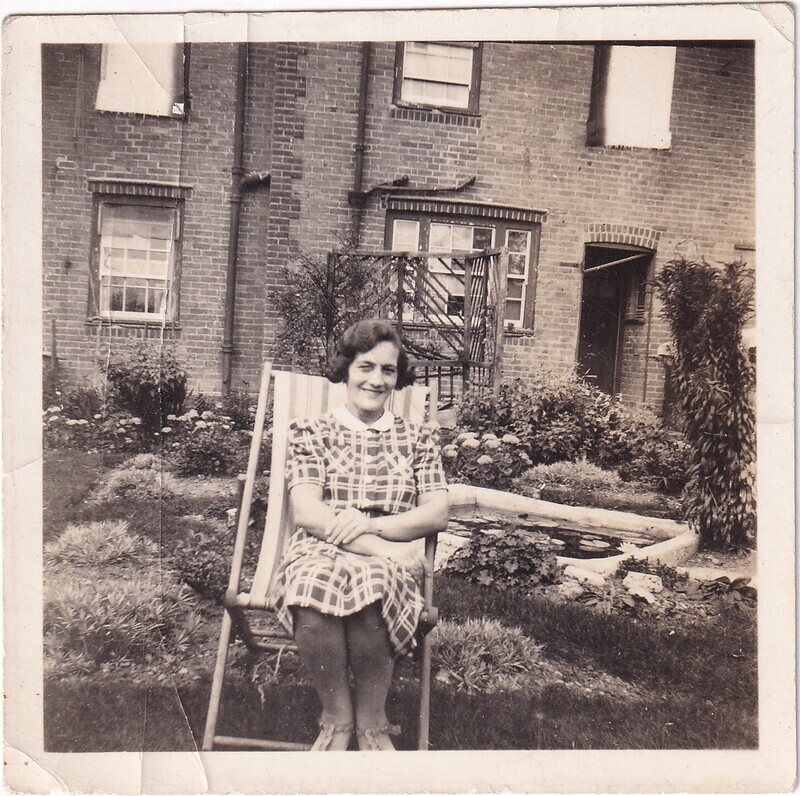 Mrs. Packer sitting in her garden, front