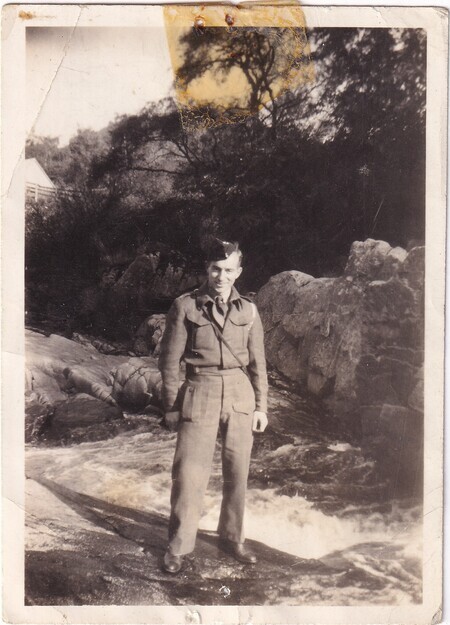 A photo of W.I. (Bill) Hann in uniform standing in front of a stream [taken in Scotland]