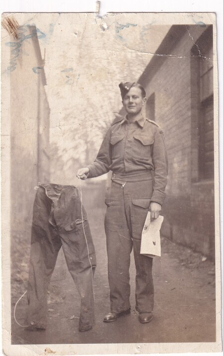 A photo of a Newfoundland soldier [Jim Winter] holding up a pair of stiffened/frozen pants [taken in Scotland]