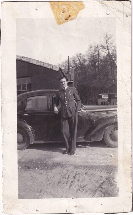 A photo of an unidentified man standing beside a car