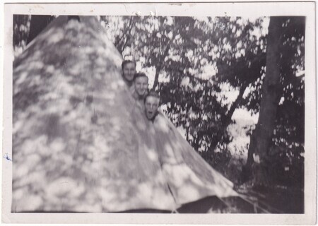 A photo of soldiers [Bill?] Butt, W.I. (Bill) Hann, and A.C. Shaw with their heads sticking out of a canvas tent taken in [East Anglia] England