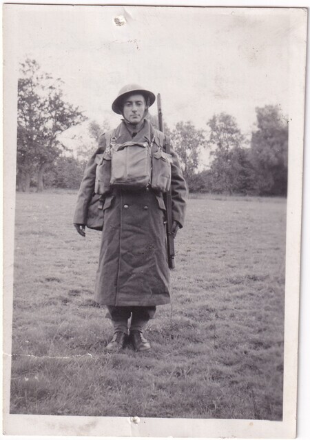 A photo of W.I. (Bill) Hann standing in a field wearing his army uniform in full kit standing at attention taken in [East Anglia] England
