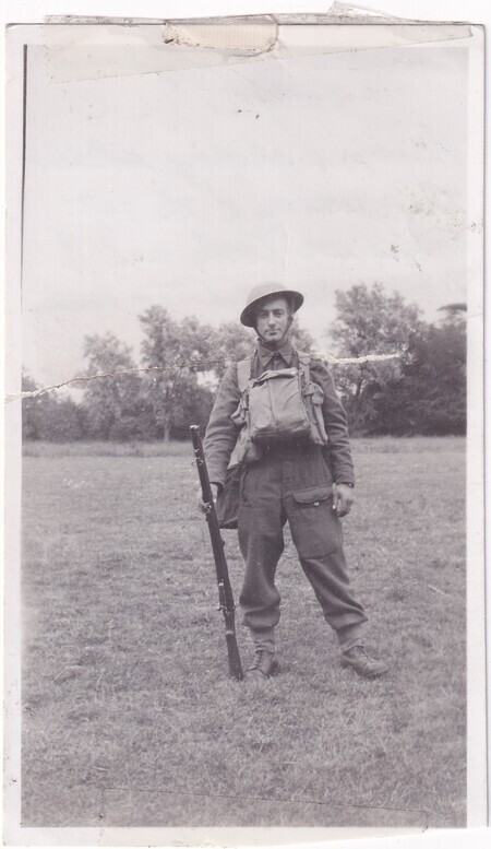 A photo of W.I. (Bill) Hann standing in a field wearing his army uniform in full kit taken in [East Anglia] England