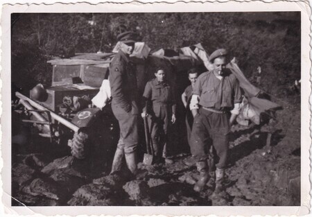 A photo of a group of Newfoundland soldiers beside a truck driving through the mud taken in Italy